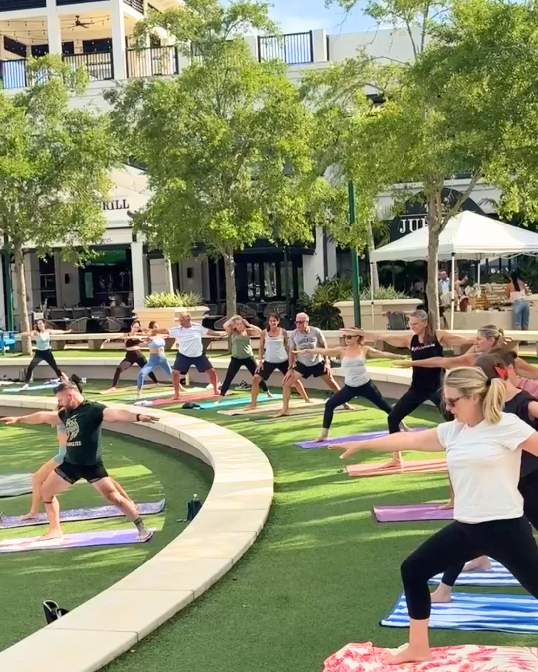 A group of people practicing yoga in front of the amphitheater at Harbourside Place.