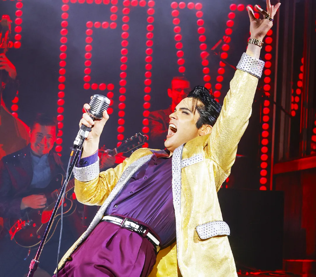 Daniel Durston performing as Elvis Presley on stage with a live band.
