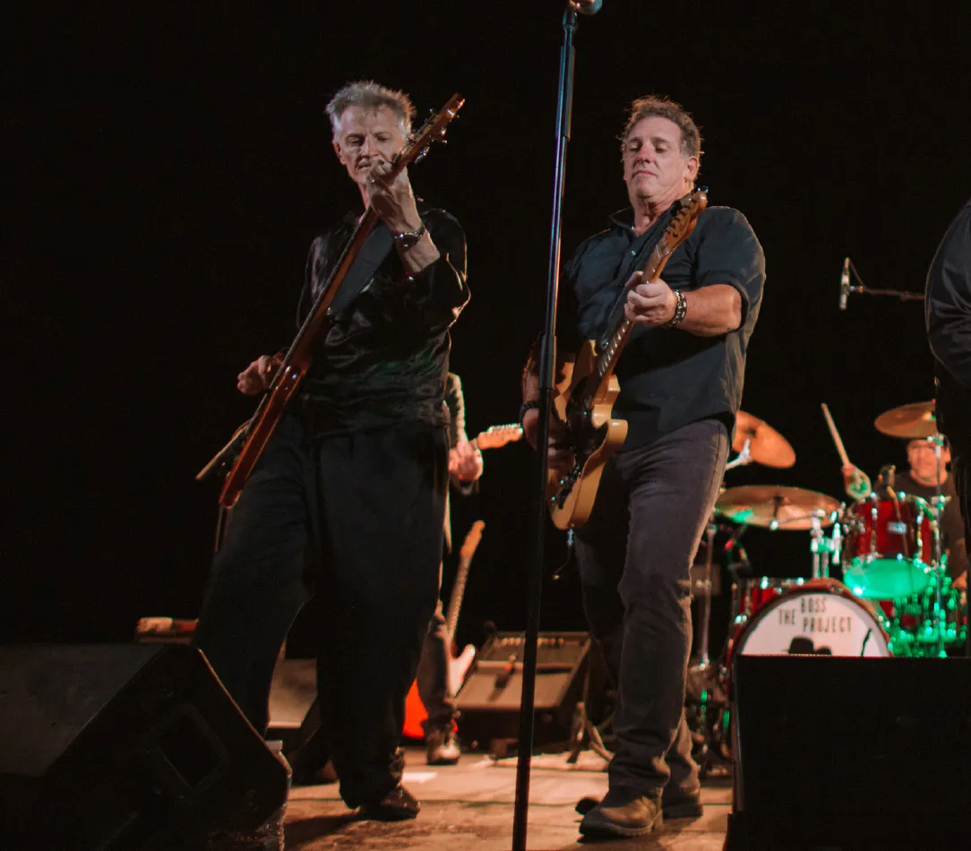 A tribute band performing on stage with a crowd in front of them.