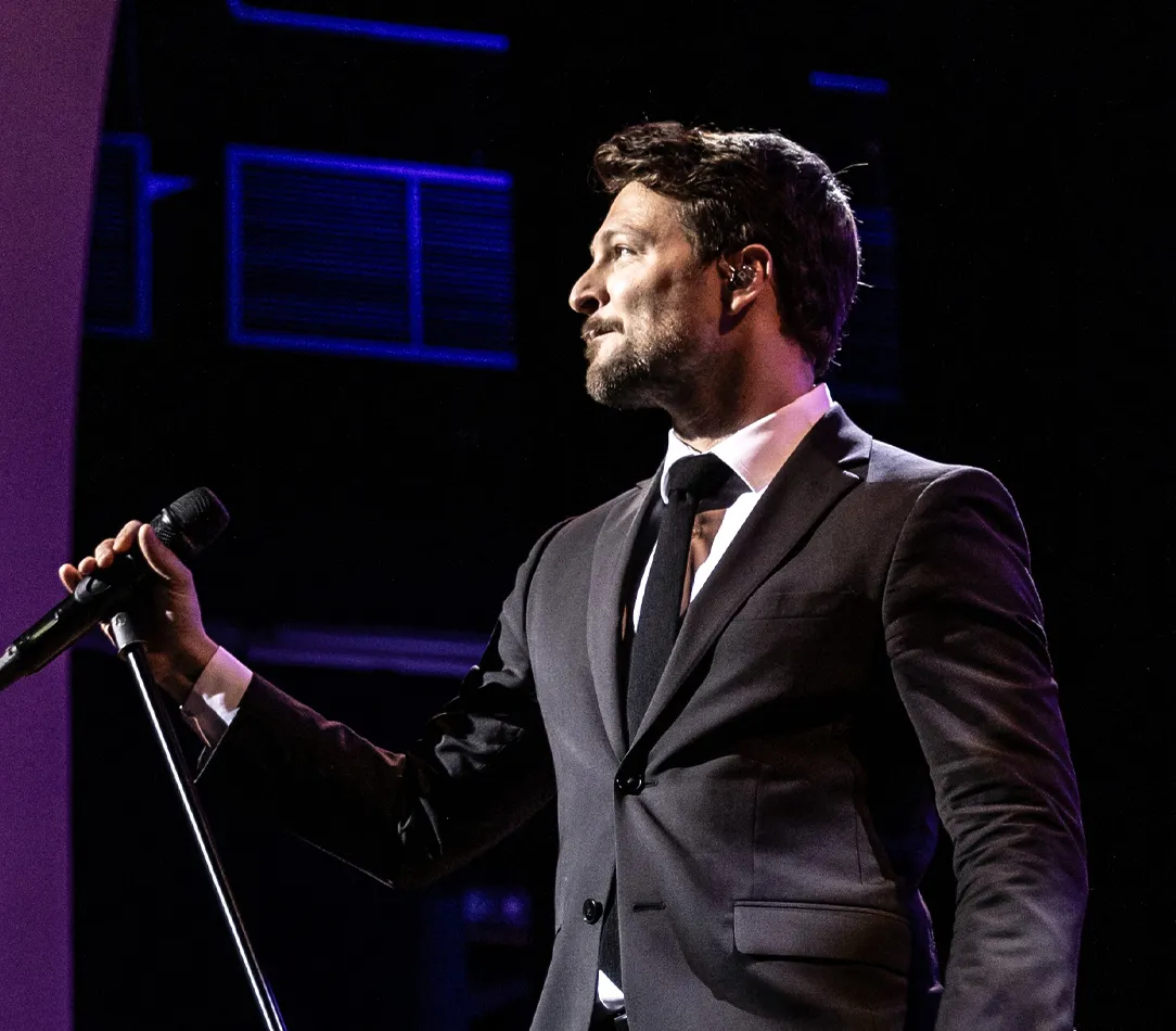 A performer on stage singing with a quartet in the background.